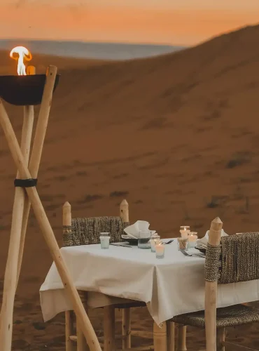 Private candlelit romantic dinner table set in the Sahara dunes at Camp Sakura
